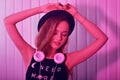 Fashion pretty cool woman in hat and headphones listening to music over pink neon background. Beautiful young teenage girl in hat Royalty Free Stock Photo