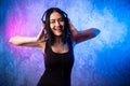 Fashion pretty cool woman in headphones listening to music over pink and blue neon background. Beautiful young teenage Royalty Free Stock Photo