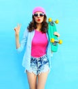 Fashion pretty cool woman in pink clothes with skateboard over colorful blue Royalty Free Stock Photo
