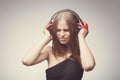 Fashion pretty girl listening music with headphones, wearing red gloves, and disappointed with bad music. Lifestyle woman concept Royalty Free Stock Photo