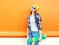 Fashion pretty girl with skateboard over colorful orange background Royalty Free Stock Photo