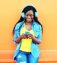 Fashion pretty smiling african woman with headphones listens to music over orange Royalty Free Stock Photo