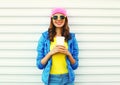 Fashion pretty smiling woman with coffee cup in colorful clothes over white background wearing a pink hat yellow sunglasses Royalty Free Stock Photo