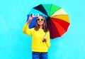 Fashion pretty smiling woman with colorful umbrella taking autumn photo makes self portrait on smartphone over blue background Royalty Free Stock Photo