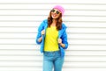 Fashion pretty smiling woman model in colorful clothes posing over white background wearing a pink hat yellow sunglasses Royalty Free Stock Photo