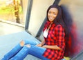 Fashion pretty smiling young african woman wearing a red checkered shirt sitting Royalty Free Stock Photo