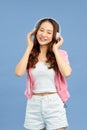 Fashion pretty sweet carefree woman listening music in headphones with smartphone wearing a colorful pink jacket, white t-shirt Royalty Free Stock Photo