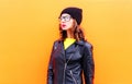 Fashion pretty woman in black hat and rock jacket over colorful orange background Royalty Free Stock Photo