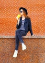 Fashion pretty woman in black rock style sitting resting drinking fruit juice from cup over background