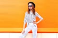 Fashion pretty woman model wearing a black hat sunglasses white pants over colorful Royalty Free Stock Photo