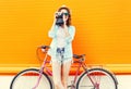 Fashion pretty woman with retro camera and bicycle over colorful orange