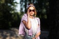 Fashion pretty woman in stylish sportswear with jeans shorts puts on sunglasses and walks outdoors Royalty Free Stock Photo