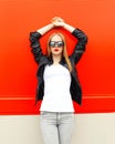 Fashion pretty woman wearing a rock black jacket and sunglasses in city over red Royalty Free Stock Photo