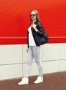 Fashion pretty woman wearing a rock black leather jacket, sunglasses and bag walking in city Royalty Free Stock Photo