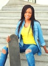 Fashion pretty young african woman with skateboard sitting Royalty Free Stock Photo