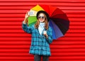 Fashion pretty young smiling woman with colorful umbrella taking picture self portrait on smartphone wearing black hat coat jacket Royalty Free Stock Photo