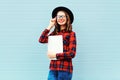 Fashion pretty young smiling woman holding laptop computer or tablet pc in city, wearing a black hat, red checkered shirt Royalty Free Stock Photo