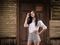 Fashion pretty young woman posing outdoor near a old wooden wall Royalty Free Stock Photo