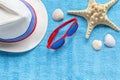 Fashion red glasses, straw hat, starfish, shells on blue beach towel. Concept travel vacation, summer holidays, top view, flat lay