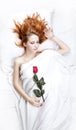 Fashion red-haired girl with rose in the bedroom.