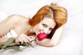 Fashion red-haired girl with rose in the bedroom.