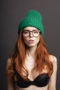 Fashion redhead Girl in Knitted Hat and galsses on grey background