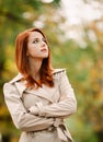 Fashion redhead woman in cloak in park Royalty Free Stock Photo