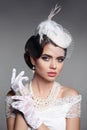 Fashion Retro elegant woman portrait. Wedding hairstyle. Brunette bride model present white hat, gloves and pearls jewelry access Royalty Free Stock Photo