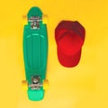 Fashion set. Skateboard and baseball cap over yellow background, top view. Royalty Free Stock Photo
