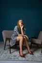 Fashion shoot of glamorous blonde woman wears silk dress and sits in a chair Royalty Free Stock Photo