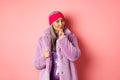 Fashion and shopping concept. Stylish old asian lady in purple fake-fur coat looking intrigued, interested with Royalty Free Stock Photo