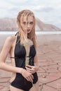 Fashion shot of beautiful blonde girl black bathing suit with a bright make-up on a background of mountains in pustyle Royalty Free Stock Photo