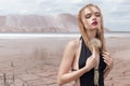 Fashion shot of beautiful blonde girl black bathing suit with a bright make-up on a background of mountains in pustyle Royalty Free Stock Photo