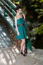 Fashion slim woman wearing green dress standing against bridge Royalty Free Stock Photo