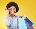 Fashion, smile and black woman with shopping bags, happy and excited for sale in studio on yellow background. Sunglasses Royalty Free Stock Photo