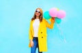 Fashion smiling woman holds an air balloons wearing a yellow coat Royalty Free Stock Photo