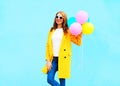 Fashion smiling woman holds an air balloons in yellow coat Royalty Free Stock Photo