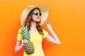 Fashion smiling woman in sunglasses and hat with pineapple over colorful orange Royalty Free Stock Photo