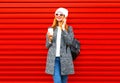 Fashion smiling woman talks on a smartphone holds coffee cup on a red