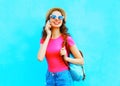 Fashion smiling young woman talking on a smartphone over a colorful blue background Royalty Free Stock Photo