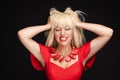 Fashion stressed blonde woman in red dress shout with open mouth holding head by hand medium closeup