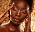 Fashion studio portrait of an extraordinary beautiful african american model with closed eyes over golden background Royalty Free Stock Photo