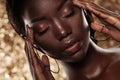 Fashion studio portrait of an extraordinary beautiful african american model with closed eyes  over golden background Royalty Free Stock Photo