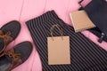 fashion stuff - bag, trousers, shoes, gift bag, note pad on pink wooden background