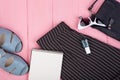 fashion stuff - bag, trousers, sunglasses, nail polish, sandals, blank note pad on pink wooden background Royalty Free Stock Photo