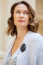 Beautiful middle-aged woman in gray knitted overcoat with black brooch