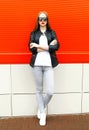 Fashion stylish woman wearing a rock black jacket and sunglasses in city over red Royalty Free Stock Photo