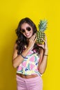 Fashion summer portrait smiling indian girl in sunglasses and pineapple over yellow background Royalty Free Stock Photo