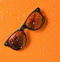 Fashion sunglasses in drops of water on a bright orange background. Royalty Free Stock Photo