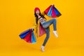 fashion teenager child girl with shopping bags on yellow background. Shopaholic shopping and fashion. Run and Royalty Free Stock Photo